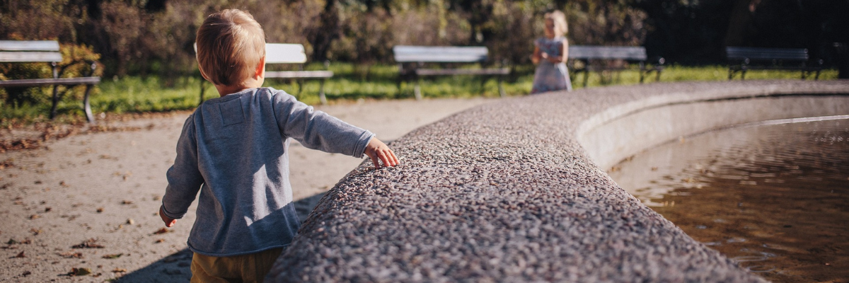 Little boy walking away alongside a fountain