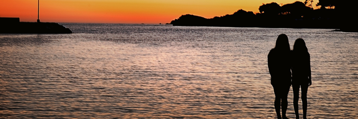 Sisters in Silhouette Looking out to Sea at Sunset