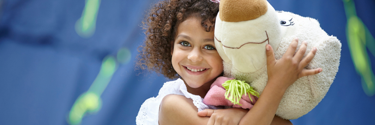 Smiling black girl hugging a large teddy
