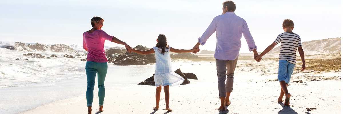 Family walking on a beach holding hands