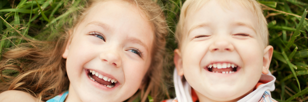 Two children lying on the grass and laughing.