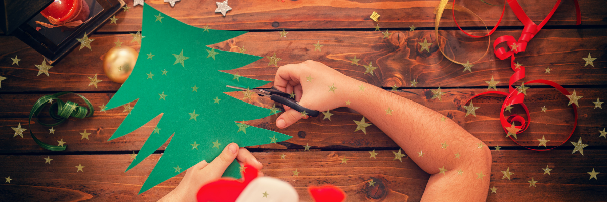 A girl cuts out a Christmas Tree our of card.