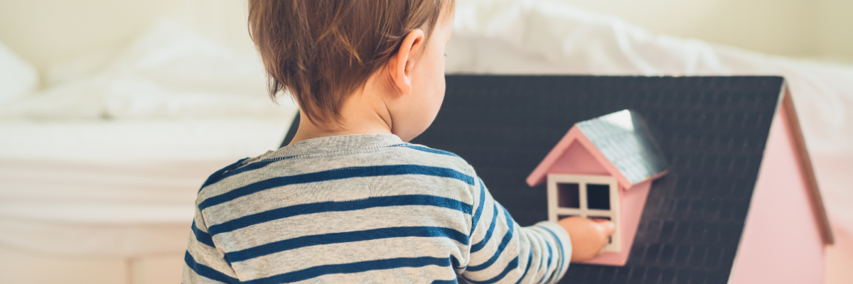 Little boy playing with a dolls house