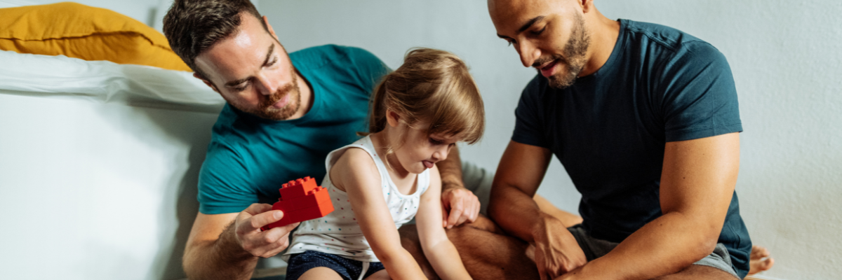 Two Dads playing Lego with their daughter