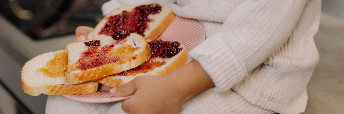 A child sits holding a jam sandwich